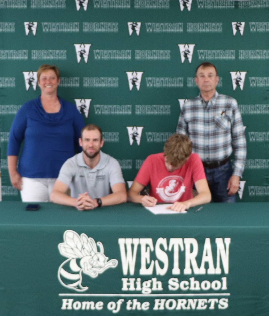 Coltin signing with his coach and parents.